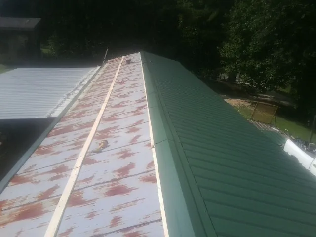 Old rusted panels beside newly installed green metal roofing — Wind Damage Roof Repair by Roofing Brothers in North Augusta