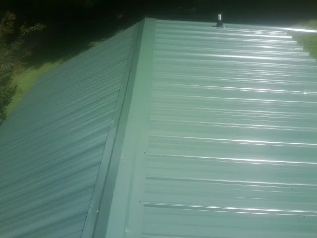 New green metal panels meeting at the ridge of a roof — Flat Roof Repair work by our crew in North Augusta