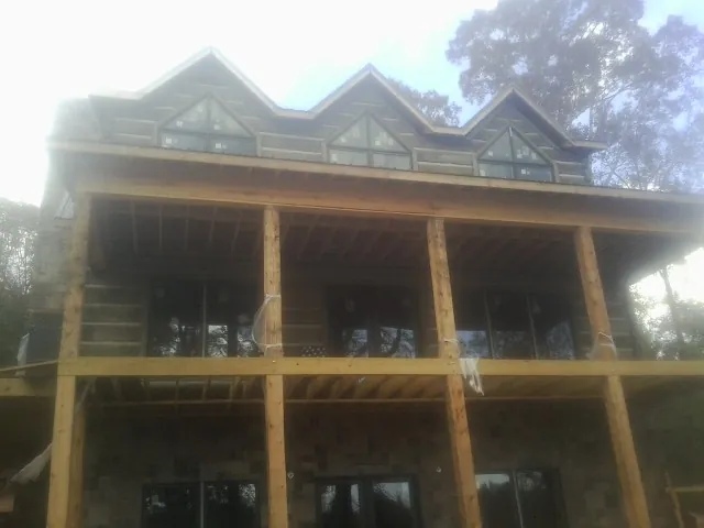 Dormers and porch framing on a large log home under construction — Roof Coating work by our crew in North Augusta