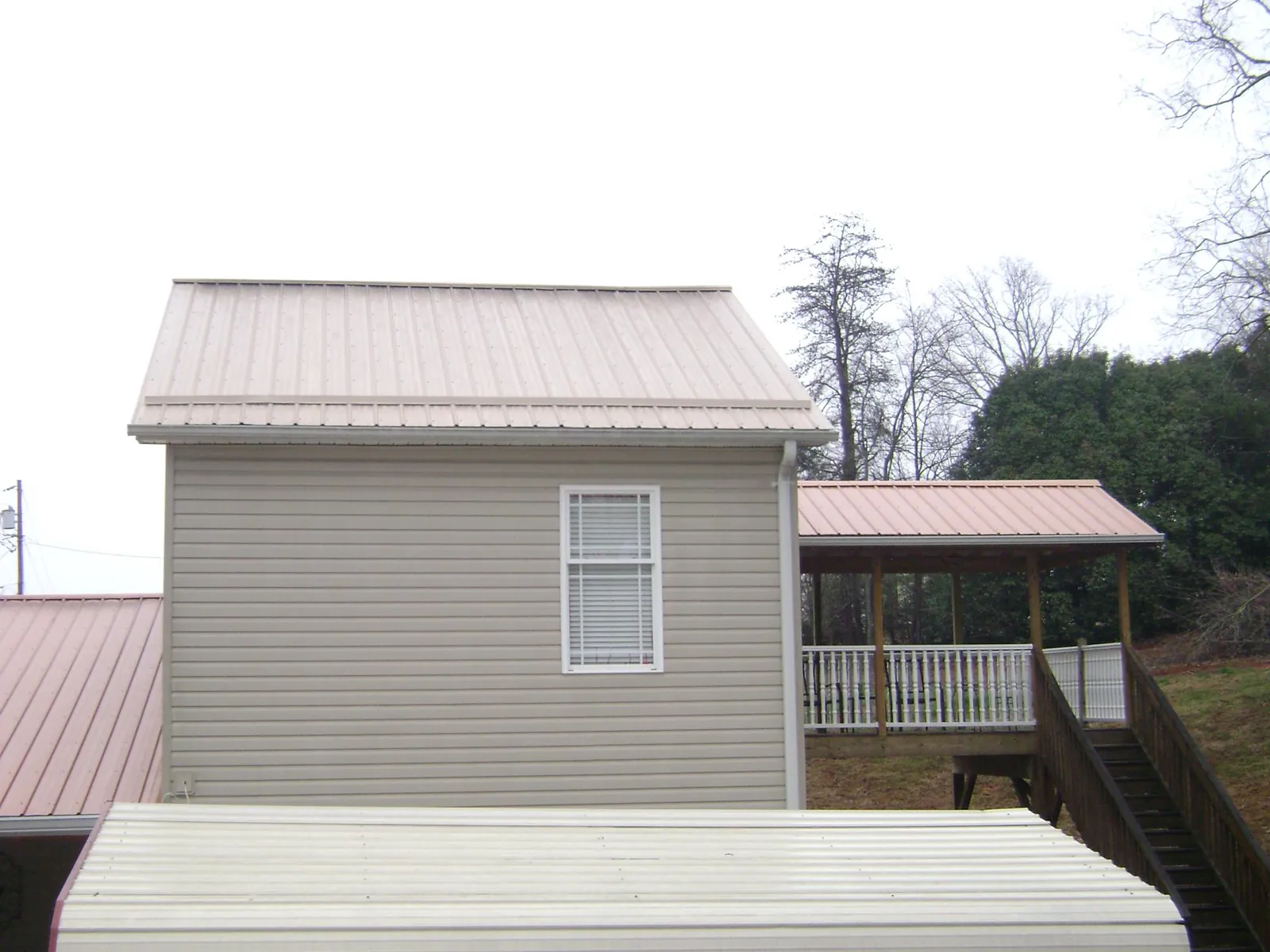 Tan metal roofs on a two story addition and attached porch, from a Roof Replacement job in North Augusta